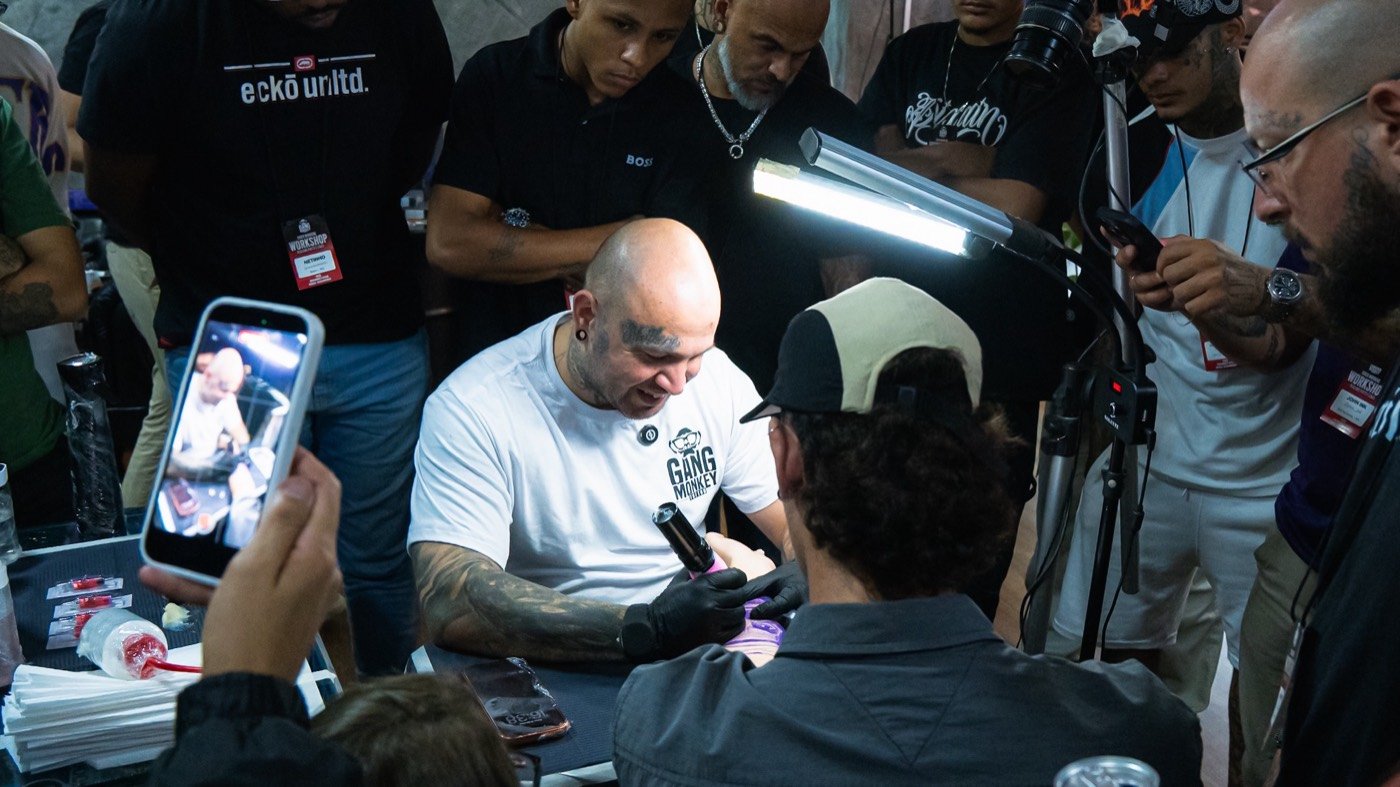 Chico Morbene tatuando cercado de tatuadores em um workshop do Grupo Morbene.